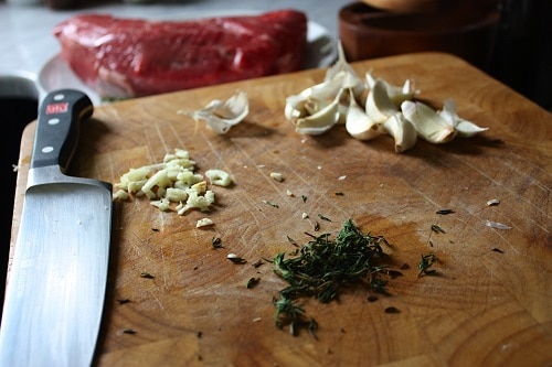 Preheat oven to 400 degrees F. Smash and mince 6 cloves of garlic. Next, strip the leaves off of 4 -6 thyme sprigs and finely chop.