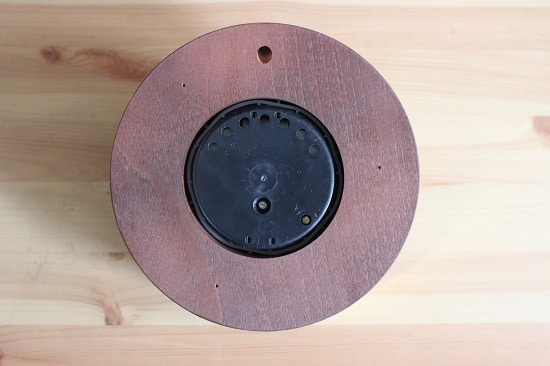 The back of an aneroid barometer. The holes at the top of plastic backing allow for air to flow through. The small screw on the bottom right edge is what's used to calibrate the device; I had to use a small eyeglass screwdriver to do so. 