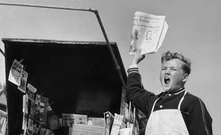 vintage paper boy selling newspapers from a stand