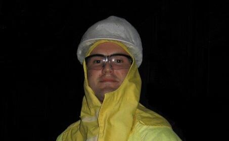 A Nuclear Engineer in a yellow protective suit standing at night.