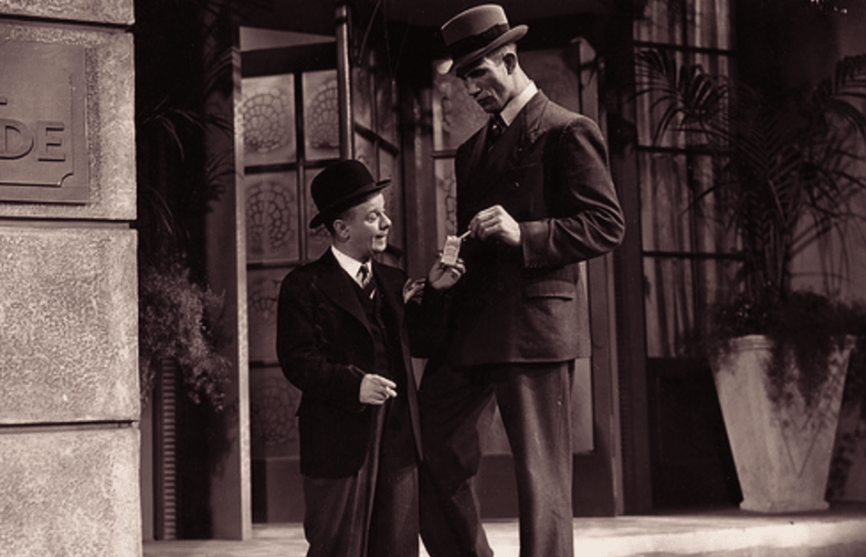 Two well-dressed men in suits and hats are standing next to each other.