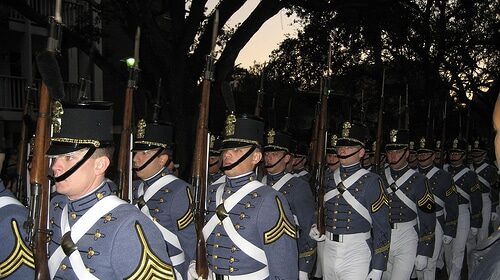 A group of senior military college soldiers in uniform marching down the street with manly determination.