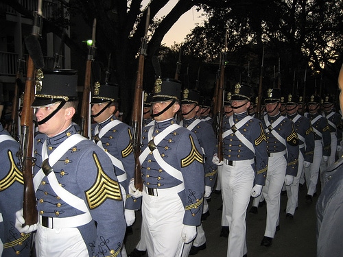 A group of senior military college soldiers in uniform marching down the street with manly determination.