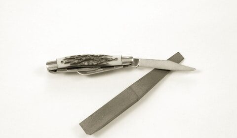 A sharpened pocket knife with a blade on a white background.
