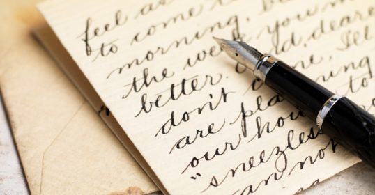A fountain pen sits on top of a piece of paper, waiting to write a love letter.