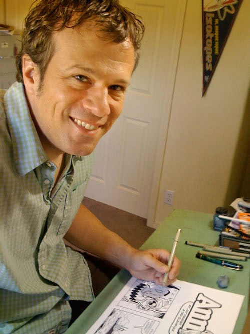 An artist sitting at a desk, working on a cartoon illustration for his job.