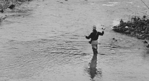 A man wading through a flooded river, with a determined mind.