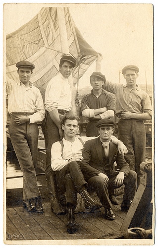 A group of John Brookes and his friends posing on a boat, exuding manliness.
