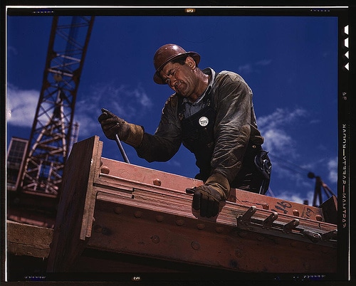 A construction worker is paying their dues as they work on an important piece of wood.