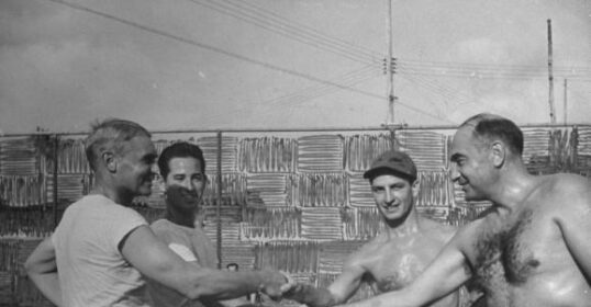 A group of men displaying sportsmanship on a tennis court.