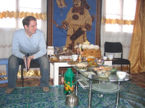 A Peace Corps Volunteer sitting in front of a table with food on it.
