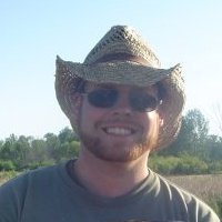 A cowboy hat-wearing man with a fish, showcasing his job as an archaeologist.