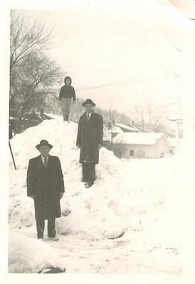 Three men showcasing their manliness, confidently standing on top of a pile of snow.