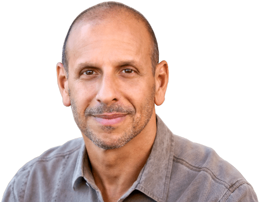 A man in a gray shirt is smiling during an interview for BetterMen.org.