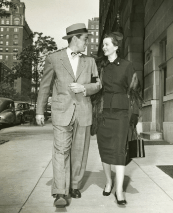 An old black and white photo of a man and woman strolling down the street on a perfect first date.