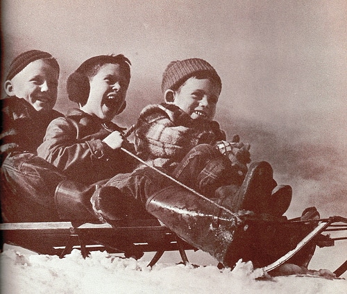 Three boys enjoying a sled ride.