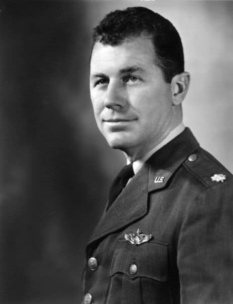 A black and white photo of a manly man in uniform.