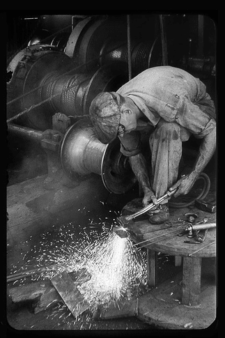 A Manvotional black and white photo of a man working on a machine with hardihood.