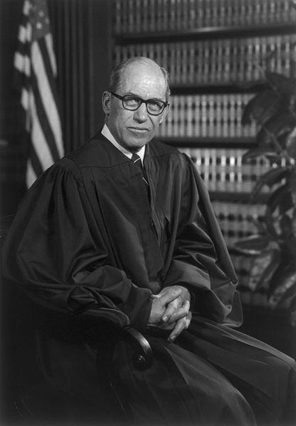 A black and white photo of a judge, showcasing manliness as he confidently sits in a chair.