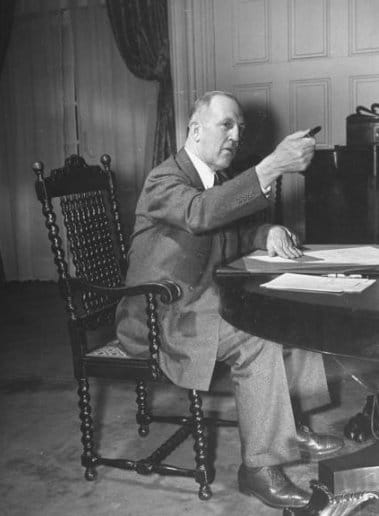 An old photo of a man showing leadership while sitting at a desk.