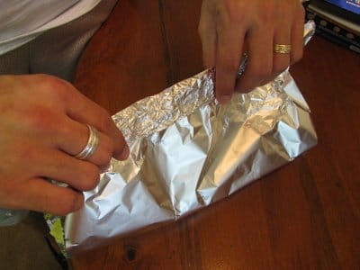 A person preparing delicious foil packet recipes around the campfire.