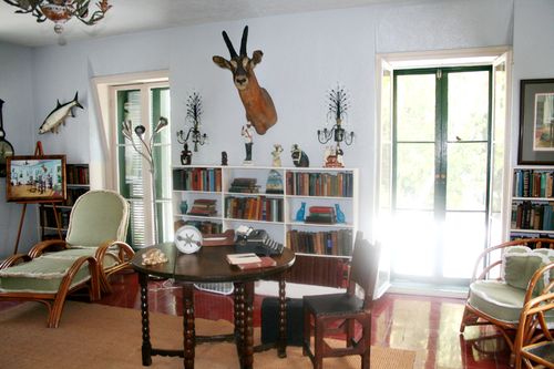 A famous man room with a table and chairs and a deer head on the wall.