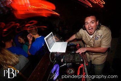 A DJ man showcasing his skills at a lively party with a laptop as his primary tool.