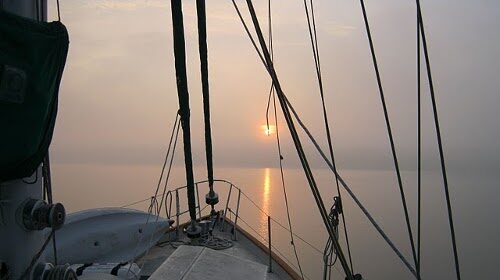 Through the bow of a sailboat, witness the show of a breathtaking sunrise, igniting passion within.