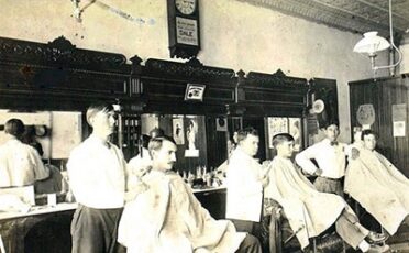 An intriguing old photo captured inside a barbershop, exuding a nostalgic atmosphere with the faint lingering smell of scented hair products and aftershave.