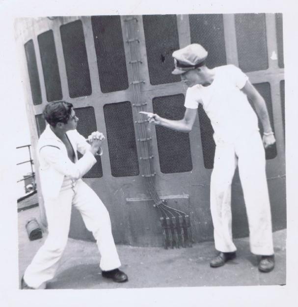 Two manly sailor men fighting in front of a ship.