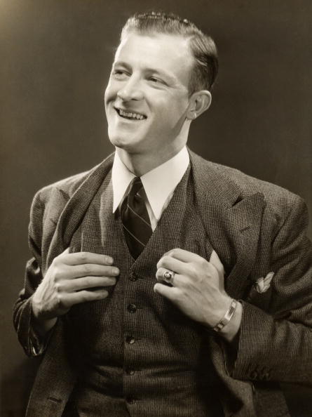A fully present man in a suit, captured in a black and white photo, with a genuine smile on his face.