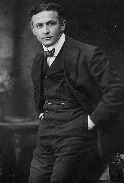 A Harry Houdini-esque man in a suit striking a pose for a photo, radiating manliness.