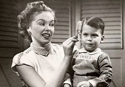 An old black and white photo capturing the tender moment of a woman brushing a child's hair.