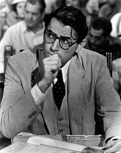 Atticus Finch, a man in glasses, sitting at a desk while imparting important lessons.