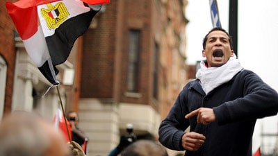 A man displaying his patriotism by proudly holding an Egyptian flag amidst the enthusiastic crowd during the Egyptian Revolution.