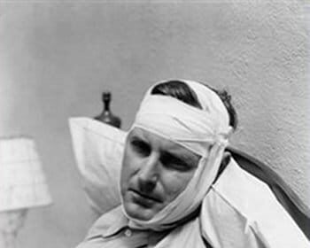 A man starting an emergency fund while laying in bed with a bandage on his head.