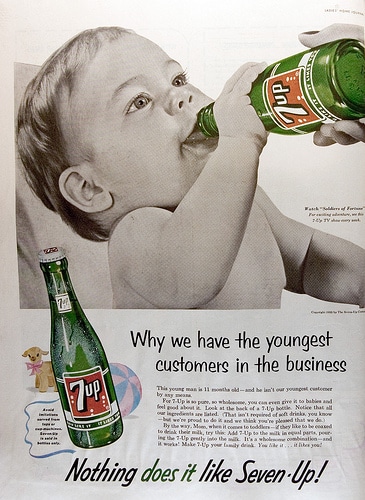 A baby, showcased in the "Man's Guide," adorably holds a bottle of seven up.