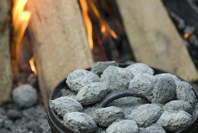 A pot full of rocks cooking over a fire in the great outdoors.