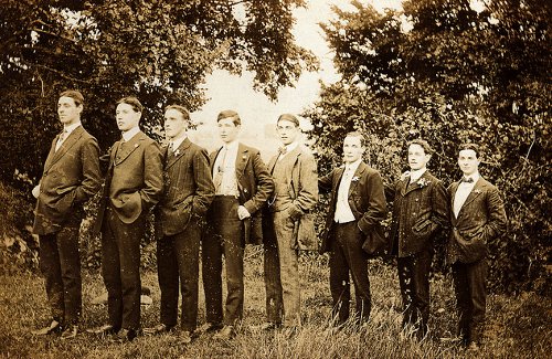 A group of tall men in suits standing in a field.