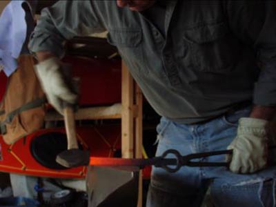 A man blacksmithing in a garage.