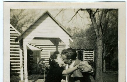 A last romantic embrace between a man and woman in front of a house.