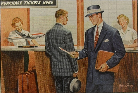 A Traveling Man in a suit and tie is talking to another man in a suit.