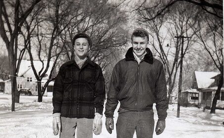 Two men, following the man's guide, standing in the snow, showcasing appropriate cold weather dressing.