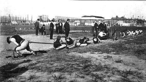 An old photo capturing the impressive display of willpower as a group of people exude a force of greatness by pulling a rope together.