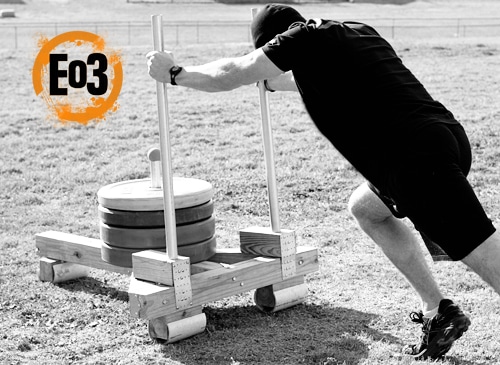 A man doing a push up on a DIY wooden platform.