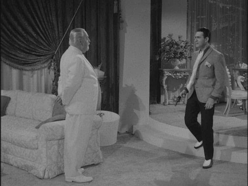 Two men standing next to each other in a sweet living room.