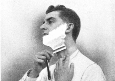 A man shaving his face with a better technique, focusing on his neck.