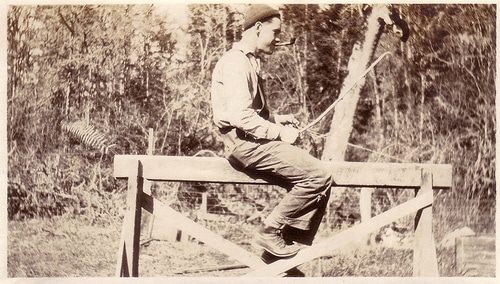 A man sitting on a strong fence.