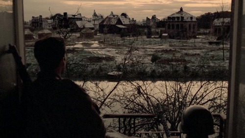 A man in Macy Falls looking out of a window at a village.