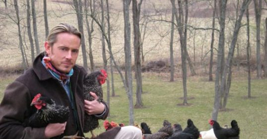 A man raising chickens in a field.